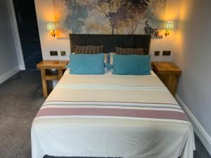 a bedroom with a large bed with blue pillows at Wheldale Hotel in Castleford