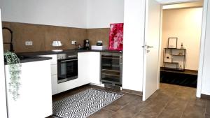 Lehmen的住宿－Casa Mo - Ferienwohnung Lehmen，厨房配有白色橱柜和瓷砖地板。