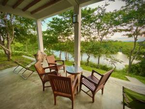 a porch with chairs and a table with a view at Kudakalliya Beach Houses in Arugam Bay
