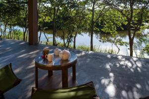 a table with cups and mugs on it next to a river at Kudakalliya Beach Houses in Arugam Bay
