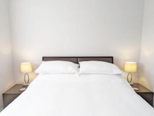 a bedroom with a large white bed with two lamps at Brook House - Emsworth in Emsworth