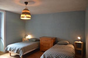 a bedroom with two beds and a light fixture at les gîtes du passage: le perchoir in Passenans +3 photos