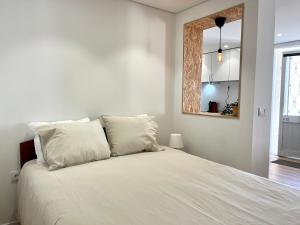 1 dormitorio con cama blanca y almohadas blancas en Casinha no caminho de Santiago, en Belinho