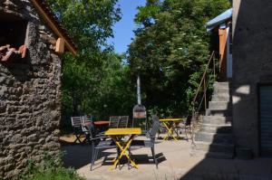 een patio met tafels en stoelen naast een stenen gebouw bij les gîtes du passage: le perchoir in Passenans