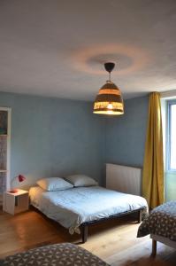een slaapkamer met een bed en een hanglamp bij les gîtes du passage: le perchoir in Passenans
