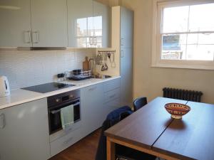 eine Küche mit weißen Schränken und einem Holztisch in der Unterkunft Stunning property overlooking local park in London