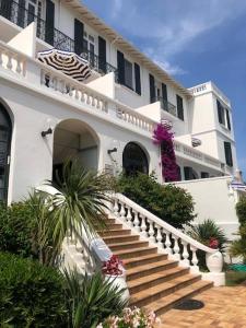 a white building with stairs in front of it at Hotel des Mimosas in Juan-les-Pins