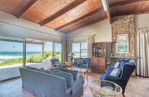 una sala de estar con muebles azules y una pared de piedra. en Anna's On The Beach, en Cape St. Francis