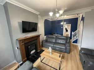 a living room with a leather couch and a fireplace at House near city centre in Hull