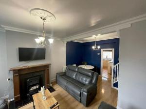 a living room with a leather couch and a fireplace at House near city centre in Hull