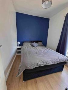 uma cama num quarto com uma parede azul em House near city centre em Hull