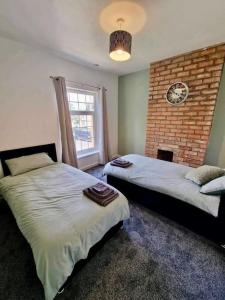 a bedroom with two beds and a brick wall at House near city centre in Hull