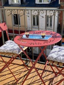 a red table and chairs with two cups on it at Nid douillet Trouville sur mer in Trouville-sur-Mer