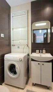 y baño con lavadora y lavamanos. en Modern Apartment SANDY BEACH down town, aquapark, free parking, en Cracovia