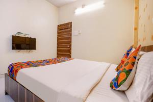 ein Schlafzimmer mit einem Bett und einem TV an der Wand in der Unterkunft FabExpress Swara Residency in Bārāmati