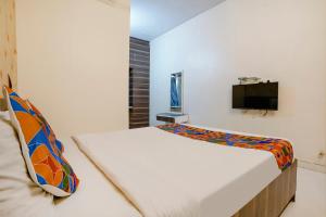 a bedroom with a bed and a tv on a wall at FabExpress Swara Residency in Baramati