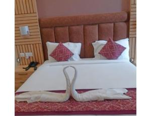 a bedroom with a large white bed with red pillows at Hotel Paras Inn, Lucknow in Lucknow