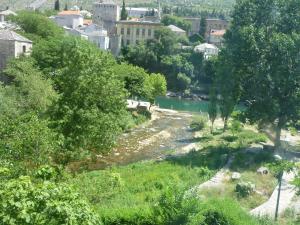 a river in a city with trees and buildings at Pansion Villa Nur in Mostar