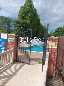 a gate to a swimming pool with the words delis den at Del's den lakeside weeley bridge in Weeley