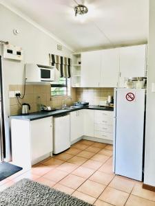 a kitchen with white cabinets and a white refrigerator at 10VDW Self Catering Apartments in Durbanville