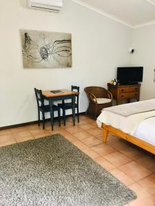 a bedroom with a bed and a table and a desk at 10VDW Self Catering Apartments in Durbanville