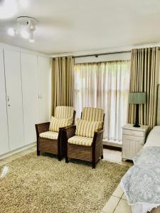 a bedroom with two chairs and a bed at 10VDW Self Catering Apartments in Durbanville