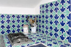 a kitchen counter with a stove and blue and white tiles at Casa Colette in Anacapri +26 photos