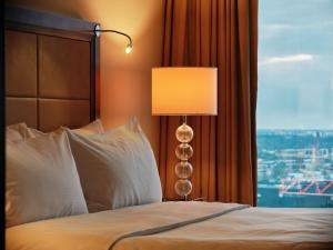 een slaapkamer met een bed met een lamp en een raam bij Hilton Warsaw City Hotel in Warschau