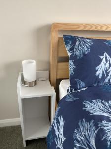 un letto con cuscino blu e bianco e un comodino di Large 2-bedroom maisonette with free parking a Twickenham