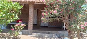 a brick house with a courtyard with trees and pink flowers at East Surf Cabanas in Arugam Bay