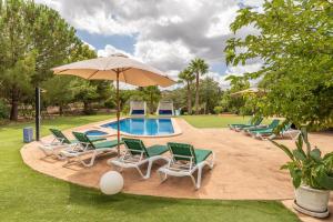 een zwembad met stoelen en een parasol en een zwembad bij La Forca in Santa Margalida