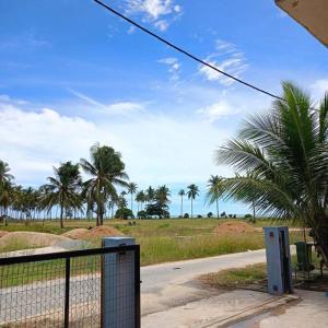 una strada con recinzione e palme su un campo di Rumah Pantai de Merabang 2 (Seaview Homestay) a Bachok