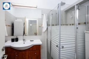 a white bathroom with a sink and a shower at Cozy Quiet Oasis in the Center in Netanya