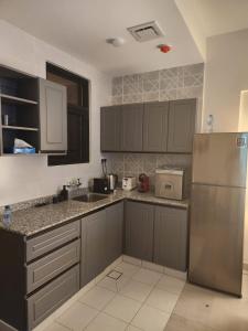 cocina con armarios grises y nevera de acero inoxidable en One Bedroom Al Hail DT, en Ḩayl Āl ‘Umayr