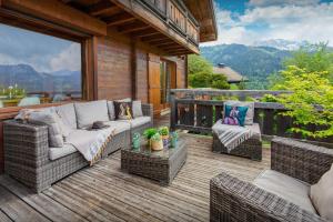 a patio with wicker furniture on a wooden deck at Chalet Isatys - OVO Network in Manigod