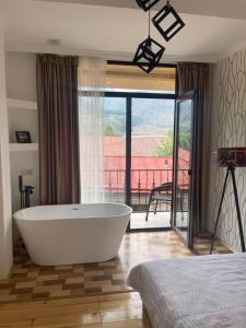 a bath tub in a bedroom with a balcony at Sunny guesthouse in Kazbegi