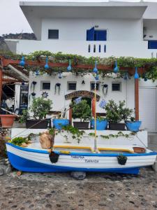 a boat parked in front of a building with potted plants at Paralia guest house in Agia Roumeli