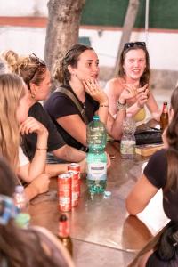 ナポリにあるNaples Experience Hostel - Age Limit 18-28の一団の女性がテーブルの周りに座り、水瓶を持って座っている