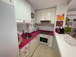 uma cozinha com armários brancos e bancadas cor-de-rosa em Apartamento Club Náutico con piscina em Denia