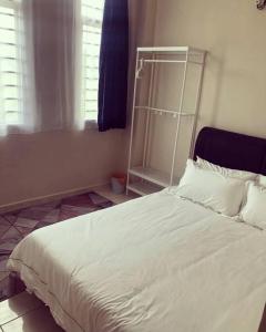 1 dormitorio con cama blanca y cabecero de metal en FaZie Homestay Seri Nuang en Shah Alam