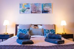 a bed with blue pillows on it with two lamps at ViVaTenerife - Cosy and elegant flat in Los Abrigos in Los Abrigos