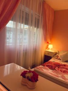 a bedroom with a bed and a window with flowers on a table at Uby House Iulius Town in Timişoara