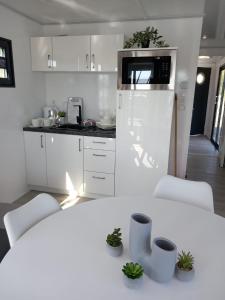 a white kitchen with a white table and chairs at Hausboat David in Hrdoňov