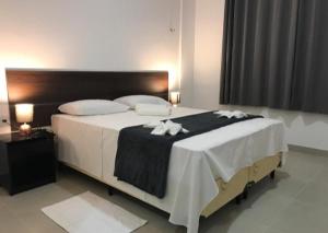 a bedroom with a large bed with a black and white blanket at Hotel Vilas in Salinópolis