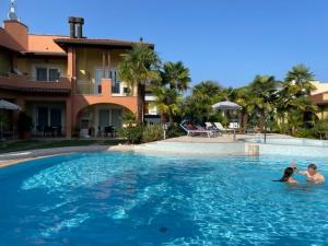 two people are swimming in a swimming pool at Corte del Mare in Aprilia Marittima