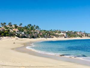 a beach with a group of people in the water at Modern 1-bedroom Apartment in Cabo San Lucas in Cabo San Lucas