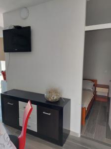 a room with a table and a red chair and a bed at Apartmani Kasteljan 12, Stara Novalja in Stara Novalja