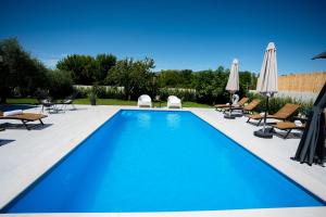 a swimming pool with chairs and umbrellas and a person sitting on a chair at Villa Musulin in Metković