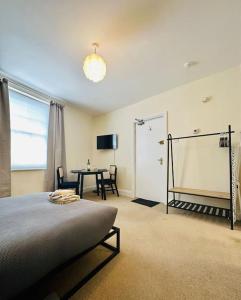 um quarto com uma cama e uma mesa com cadeiras em Studio apartment, The Suffolks. em Cheltenham