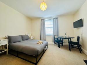 um quarto com uma cama e uma mesa com cadeiras em Studio apartment, The Suffolks. em Cheltenham